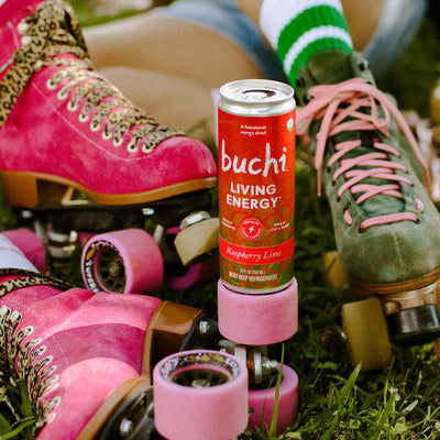 A can of Living Energy balances on the bright pink wheel of a roller skate