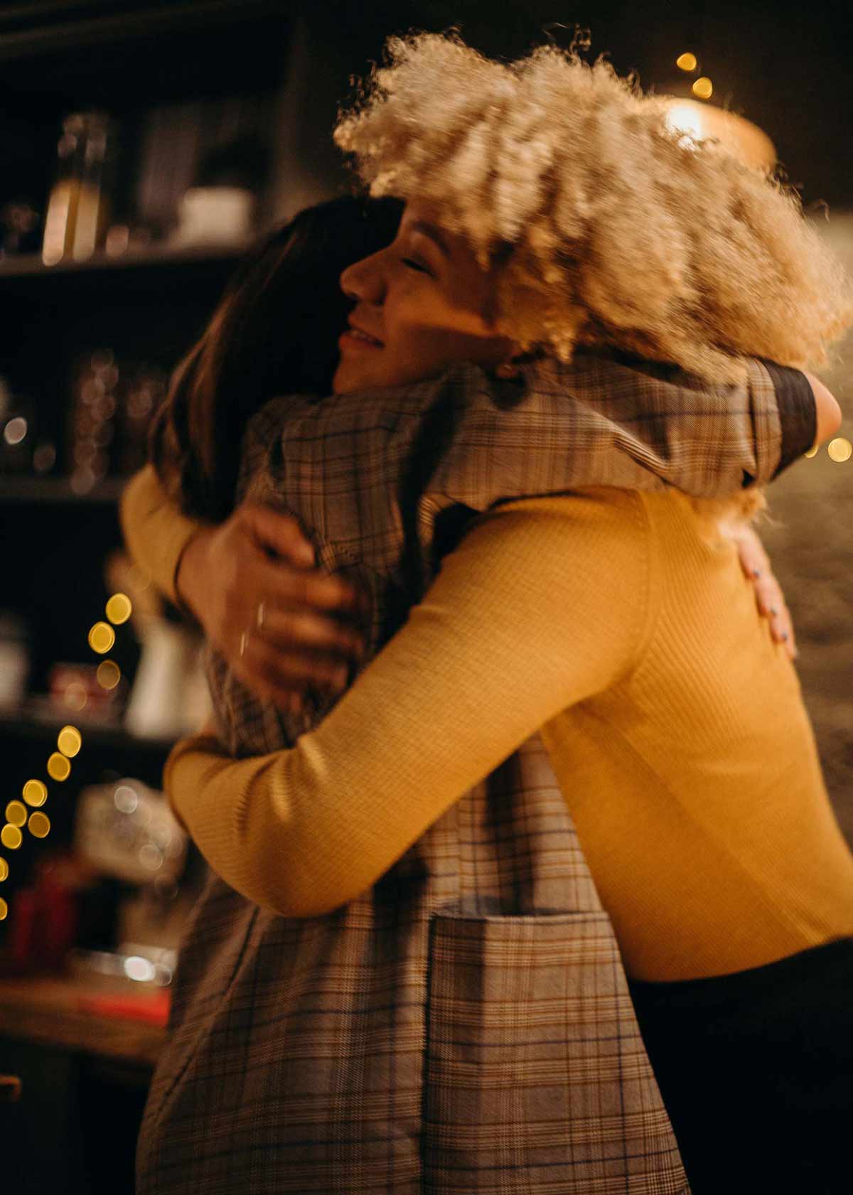 Two friends hugging in front of Holiday lights