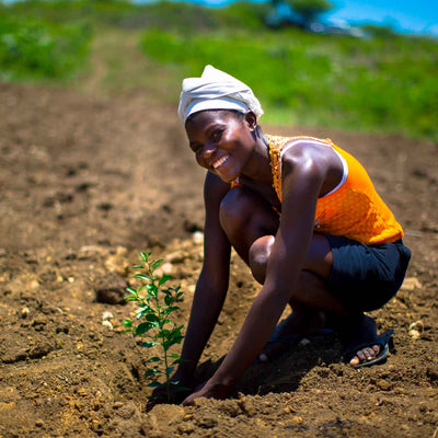 One Tree Planted: A woman planting trees, smiling at the camera